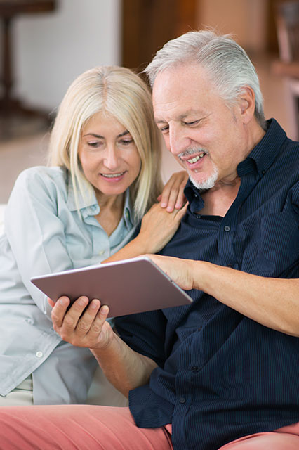 senior couple sat on the couch using table for research about bowel conditions.